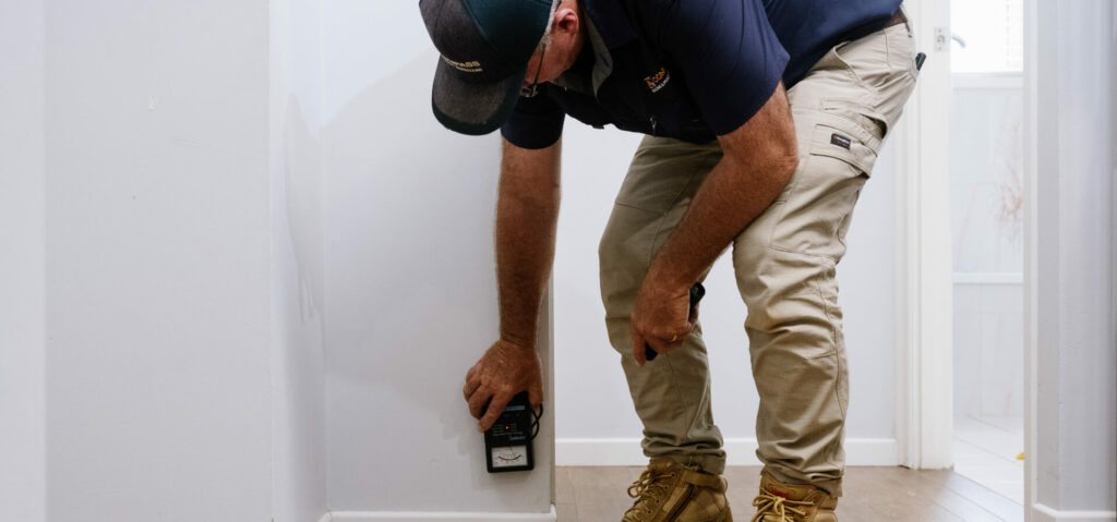 Man testing wall for termite activity