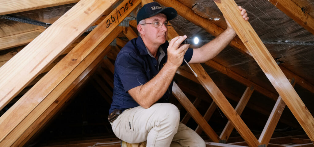 Man inside a roof cavity with a torch